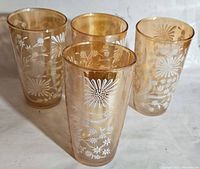 Four mid-century amber carnival glasses with white floral etching detail shown from top view and grouped view.