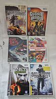 Image of 6 Nintendo Wii game cases including Transformers, Guitar Hero III, Speed Racer, Namco Museum Remix, Splinter Cell Double Agent, and Call of Duty World at War.