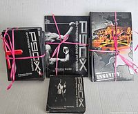 Front view of multiple workout guides and manuals for P90X and Insanity tied with pink straps.