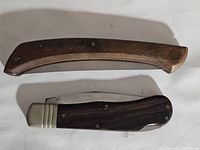 Pair of vintage pocket knives and leather sheath arranged on a flat surface