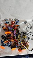 Skylanders figurines and accessories laid out on a white surface, showing a mix of character figures and portal equipment.