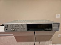 Full front view of the vintage Akai AA-A25 receiver showing its rectangular shape, silver color, and power indicator lit on the front left.