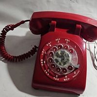 Full view of red rotary dial telephone with coiled cord and handset