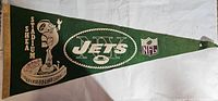 Photo of green NY Jets Shea Stadium pennant showing full design including football player and stadium illustration