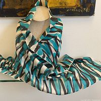 Silk scarf displayed partially draped over a surface to show pattern and fabric sheen.