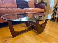 Full side view of the oval glass top and walnut base