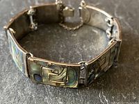 Angled view of the bracelet showing rectangular abalone inlay on sterling silver links and safety chain.