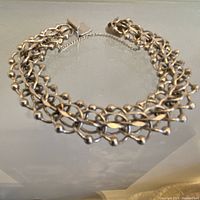 Full view of the sterling silver linked bracelet laid flat showing the linked rings with spheres and safety chain attached to clasp.