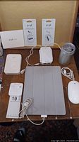 Photo of lot showing iPad, can speaker, WiFi extender, Popl cards, earphones, mouse and charging cables.