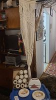 Full view of the macrame plant hanger hanging from shelf, visible crochet string rolls and ceramic dishes below