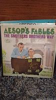 Front cover of Aesop's Fables The Smothers Brothers Way vinyl record showing illustrated image of performers and title text.