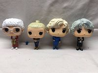 Front view of all four Funko Pops standing in a row on neutral background.