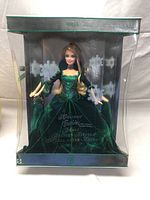 Full front view of Barbie doll in box showing green velvet gown and holiday themed box design.