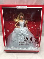 Full front view of Barbie doll in box with 25th anniversary label and holiday-themed background.