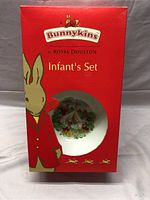 Front of original red box showing Bunnykins branding and infant bowl partially visible through window.
