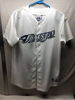Full view of white Toronto Blue Jays jersey showing front with button closure and Jays logo.