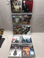 Front view of all ten PS3 game cases arranged in two columns showing covers of each title including The Walking Dead, Hitman, Plants vs Zombies, Uncharted 3, Dead Island, Kane & Lynch, Assassin's Creed, Rocksmith, and Mortal Kombat.