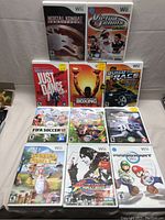 Full view of all 11 Wii game cases arranged in 3 rows on a white surface. Titles and cover art visible.