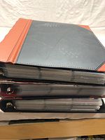 Three large binders stacked filled with hockey cards showing outer covers and some pages visible