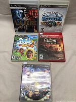 Lot of 5 PS3 games displayed on table, showing all game cases.