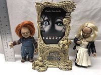 Full view of Chucky and Bride of Chucky dolls with display stand, ruler for scale showing dolls around 7 inches tall.