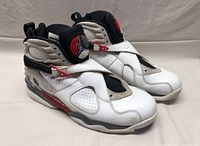 Pair of Nike Air Jordan Retro 8 sneakers in white, black and red, side and angled view showing overall condition and colors.