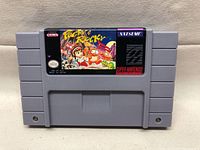 Front view of Super Nintendo cartridge showing colorful Pocky & Rocky label by Natsume with game title and Nintendo branding.