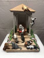 Full view of the figurine showing white cat on wicker chair inside gazebo with eleven other cats positioned around steps and side pillars with floral details on gazebo.