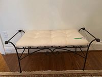 Front angle view of wrought iron bench with tufted cushion