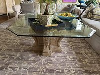 Top view of coffee table showing thick beveled glass top with a small chip and decorative composite base beneath.