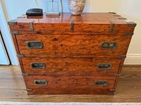 Front view of three-drawer veneer dresser with metal corner brackets and recessed pulls