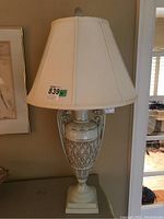 Front view of the ceramic table lamp showing its ornate urn-shaped base with crazed glaze and fabric shade.
