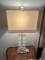 Front view of one lamp turned on showing rectangular shade and finial