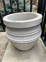 Concrete outdoor planter with rope style trim detail.
