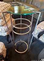 Photo of the steel side table showing the round glass top on a metal base with circular supports.