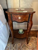 Full view of the side table showing the curved legs, faux drawer front with glass knob, and lower shelf.