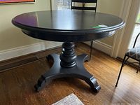 Front angle of round black pedestal table showing top and base