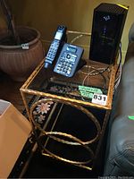 Side view of the table showing the wrought iron twisted frame, circular accents, and glass top with items on it.
