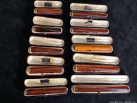 Ten amber mouthpieces in original cases arranged in rows on black surface