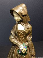 Close-up of upper torso showing bonnet, laced bodice and enamel flower bouquet