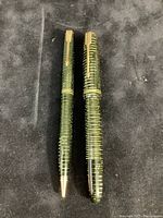 Both Parker Vacumatic fountain pen and mechanical pencil shown standing upright on black velvet surface, showing amber striated pattern and gold clips