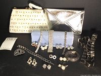 Overall view of all pieces showing two evening clutches, bracelets, earrings, cuff links, belt, brooches arranged on black background