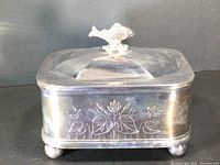 Front view of the antique silver plated sardine box showing lilypad design etching and fish-shaped lid handle.