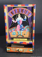 Front view of music box showing circus scene with dancing clown and drawer.