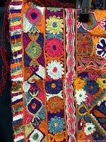 Close-up of the intricate colorful embroidery with floral and geometric patterns on the rug's edge showing detailed stitching.