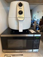 Danby microwave with Starfrit air fryer on top placed on kitchen counter.