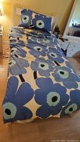 Single bed with white frame, mattress partially exposed, Marimekko floral duvet cover on bed with pillow