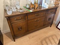 Full view of the wooden buffet showing five drawers and two cupboards with decorative hardware and finish.