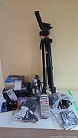 Photo showing Soludex tripod standing on table with various electronics, power cords, and label maker device.