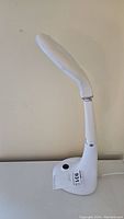 Full side view of the white magnifying lamp showing its tall adjustable arm and base with on/off button.